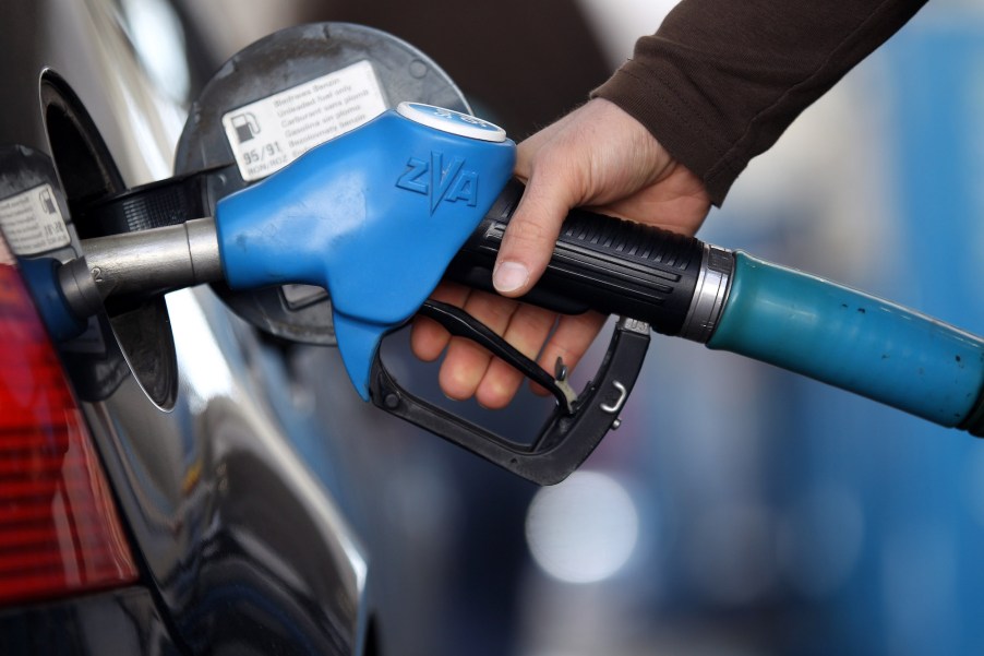 Someone pumping gas possibly deciding on buying a new car to save on gas.