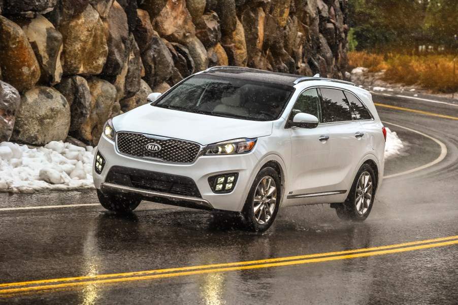 A 2018 Kia Sorento midsize SUV in white, driving on an empty road