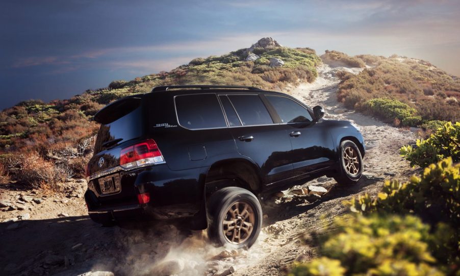 The back of a black 2021 Toyota Land Cruiser driving over a mountainous terrain.