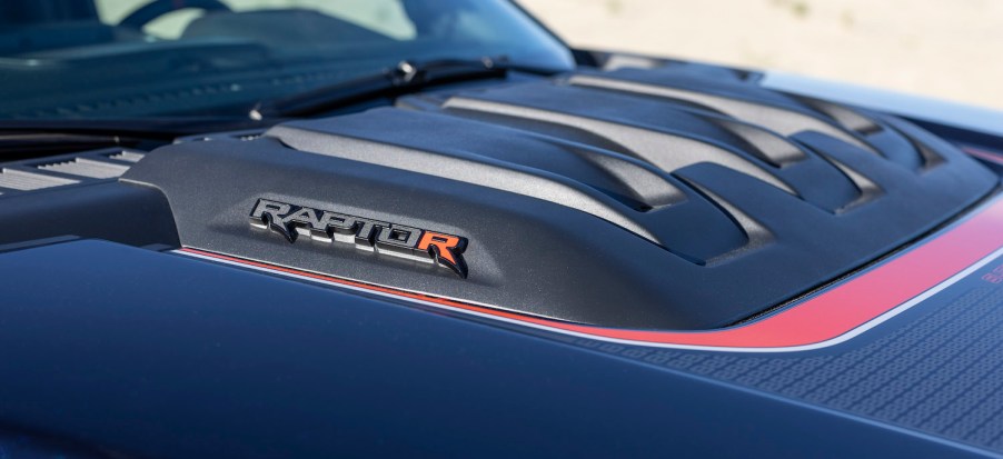 Closeup of the badges on the hood scoop of an F-150 Raptor R above its V8 engine.