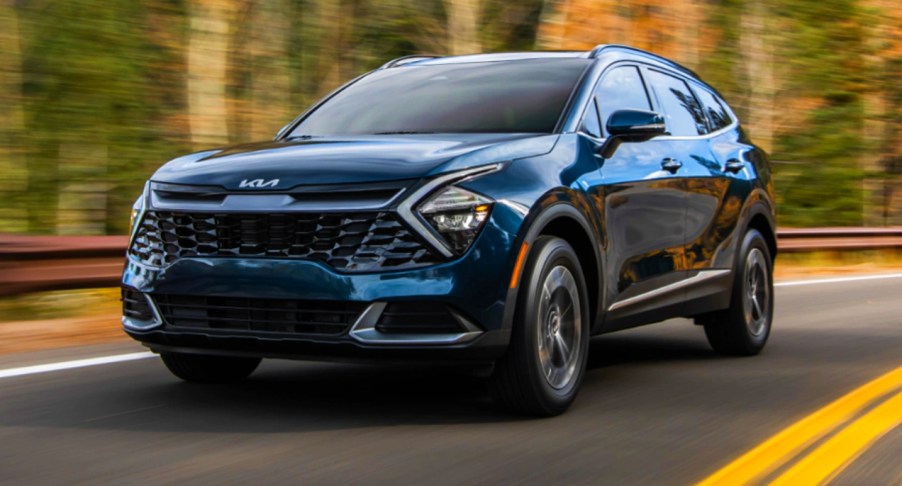 A blue 2023 Kia Sportage Hybrid SUV is driving on the road.