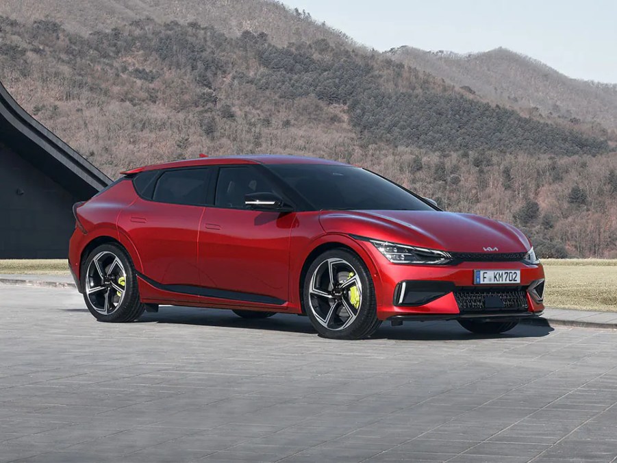 A red 2023 Kia EV6 GT sits parked in front of a mountainous terrain.