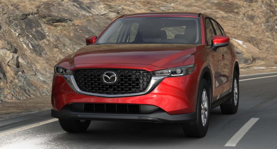 A red 2022 Mazda CX-5 small SUV is driving down the road.