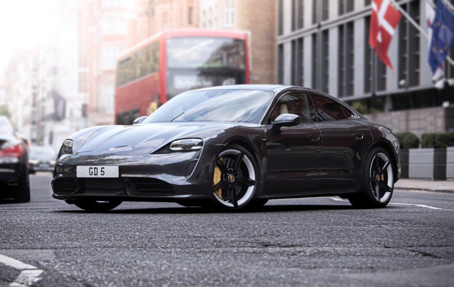 A dark colored Porsche Taycan parked in an outdoor city environment.