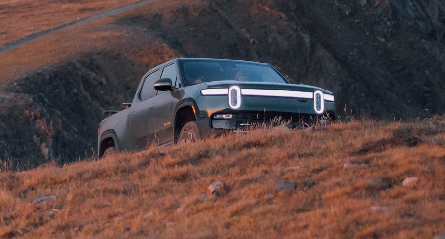 A green Rivian R1T electric pickup truck is parked outdoors.