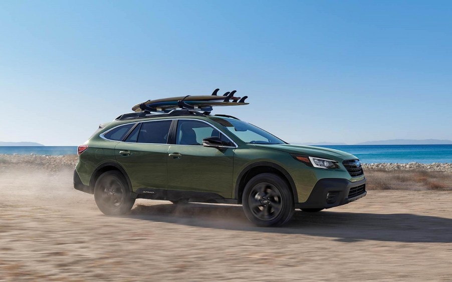 A pale green 2022 Subaru Outback driving on the beach.