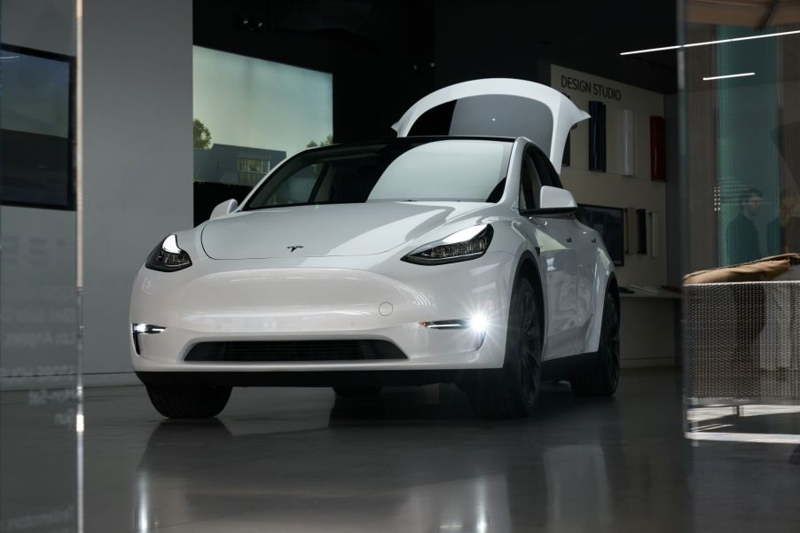 A white Tesla Model Y compact electric SUV with its trunk open on display at a shopping mall in Culver City, California