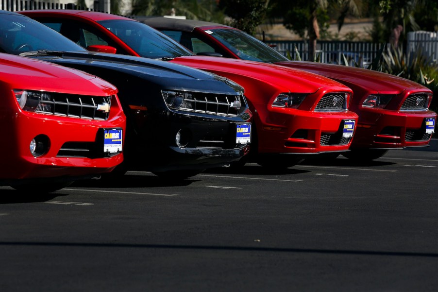 Used Chevrolet Camaros and Ford Mustangs are displayed for sale at a CarMax.