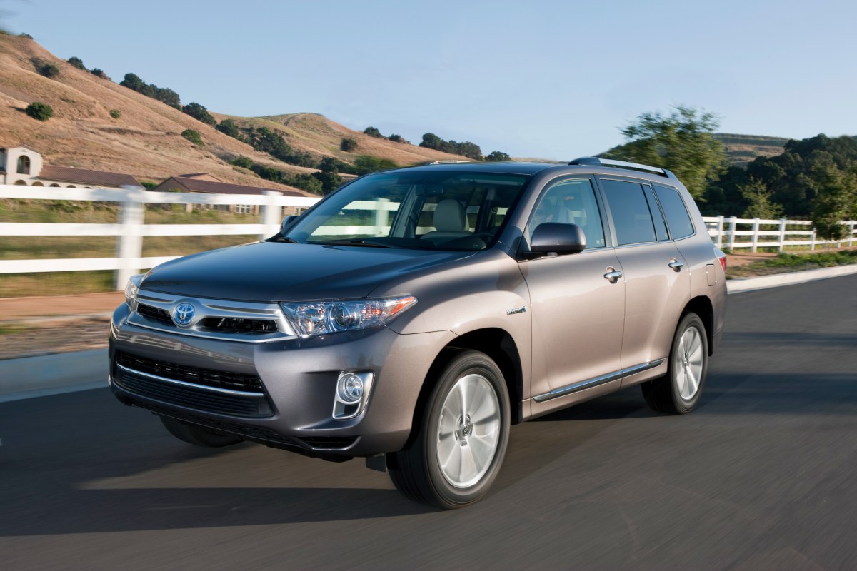 A silver 2013 Toyota Highlander Hybrid parked by a fence