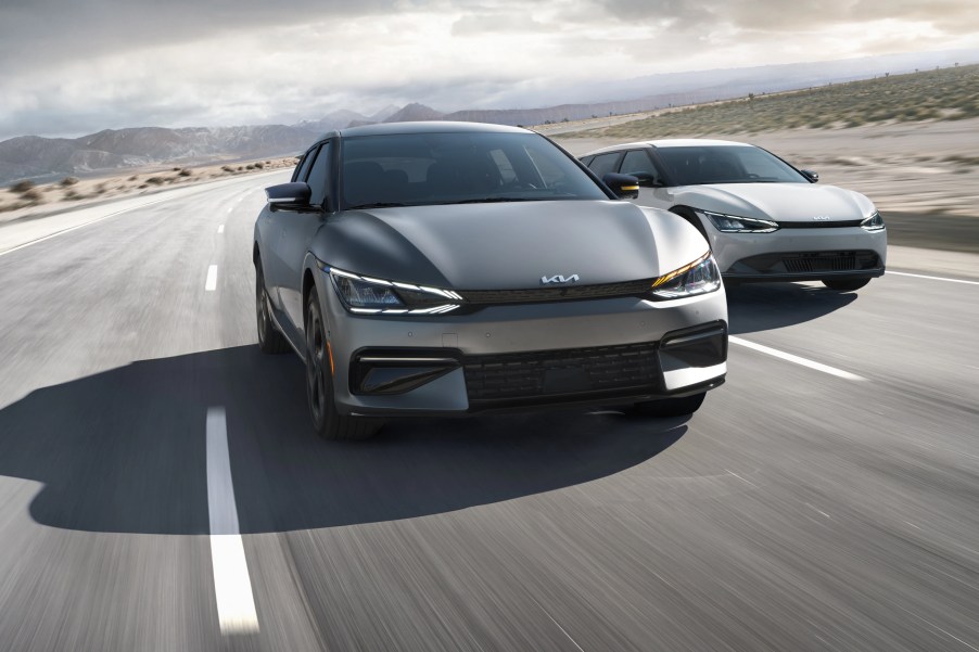 A pair of 2022 Kia EV6 models drive on a road.