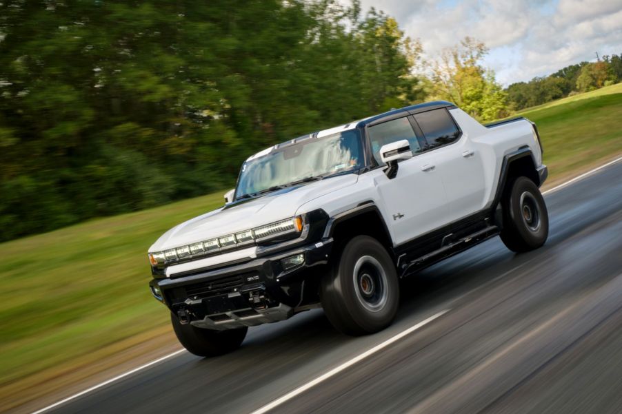 A white GMC Hummer EV pickup truck model speeding down a country highway