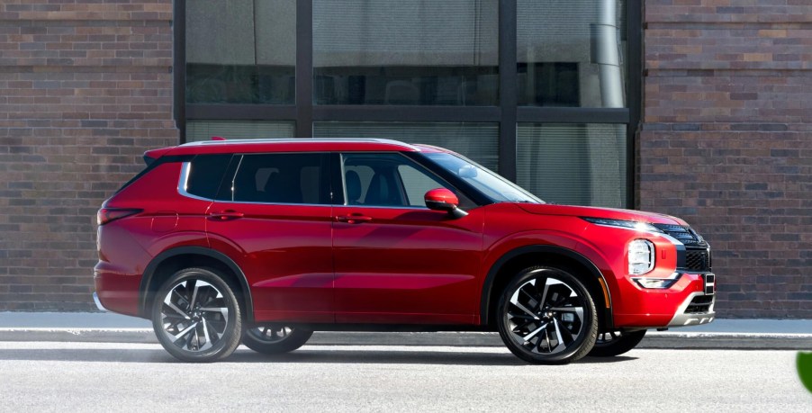 A red 2022 Mitsubishi Outlander against a city background.