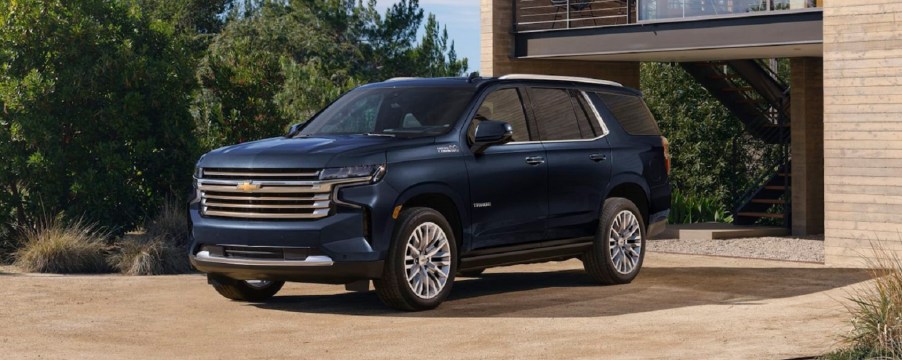 A navy blue 2023 Chevy Tahoe parked outside of a house.