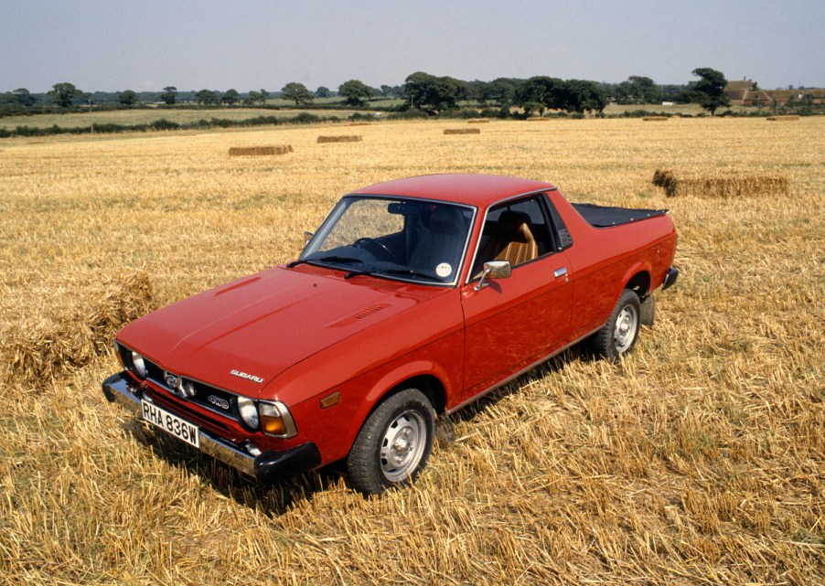 A red Subaru Brat sits in an open field as a vintage ute.