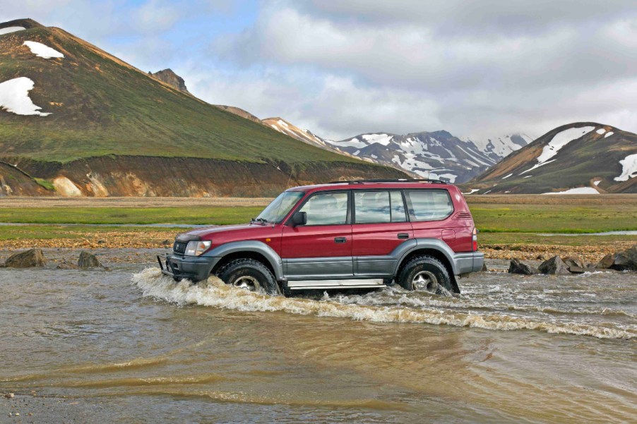 An 80-Series Toyota Land Cruiser fords a small body of water.