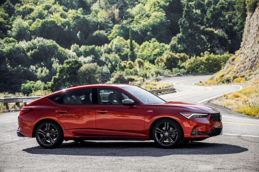 A red 2023 Acura Integra A-Spec compact liftback coupe model parked on the side of a curving highway road