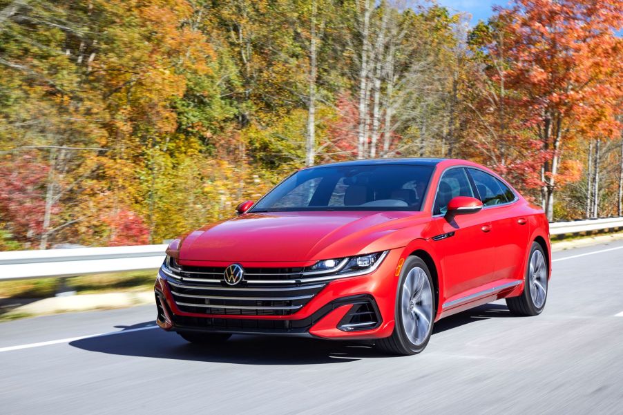 A red 2021 Volkswagen Arteon liftback luxury sedan model driving on a highway near autumn trees