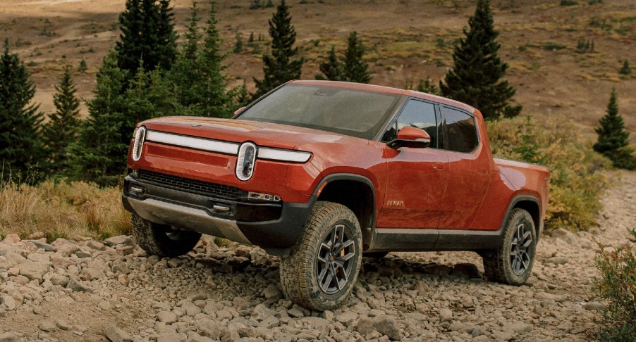 A red Rivian R1T electric truck is driving off-road.