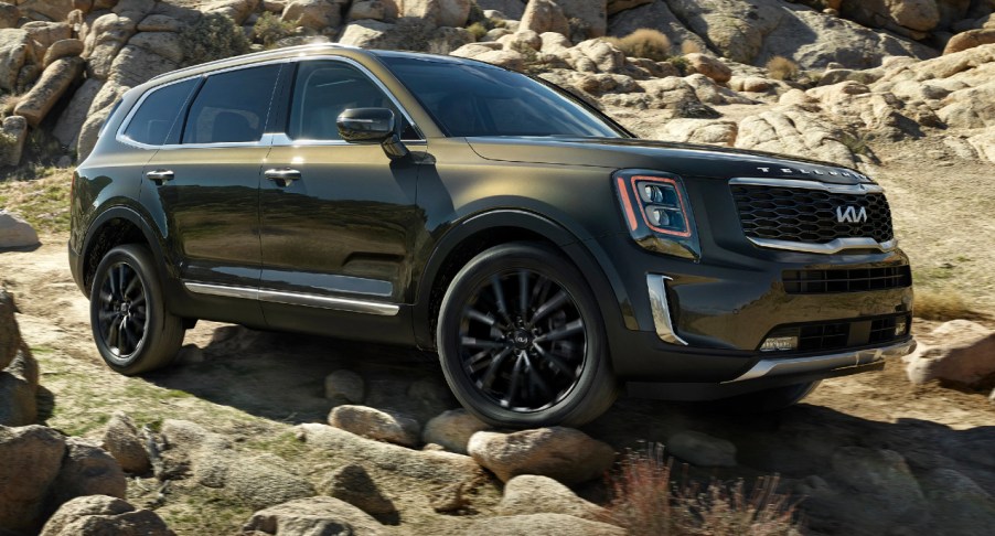 A green 2022 Kia Telluride midsize SUV is driving off-road.