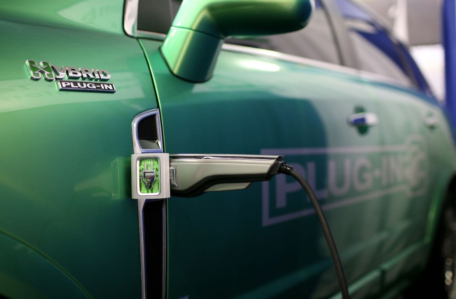 Closeup of a plug-in hybrid's charger set into its green fender, PHEV badge visible in the foreground.