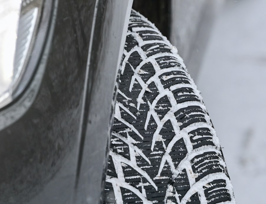 The tread of a winter tire on a car has been clogged by snow on the road.