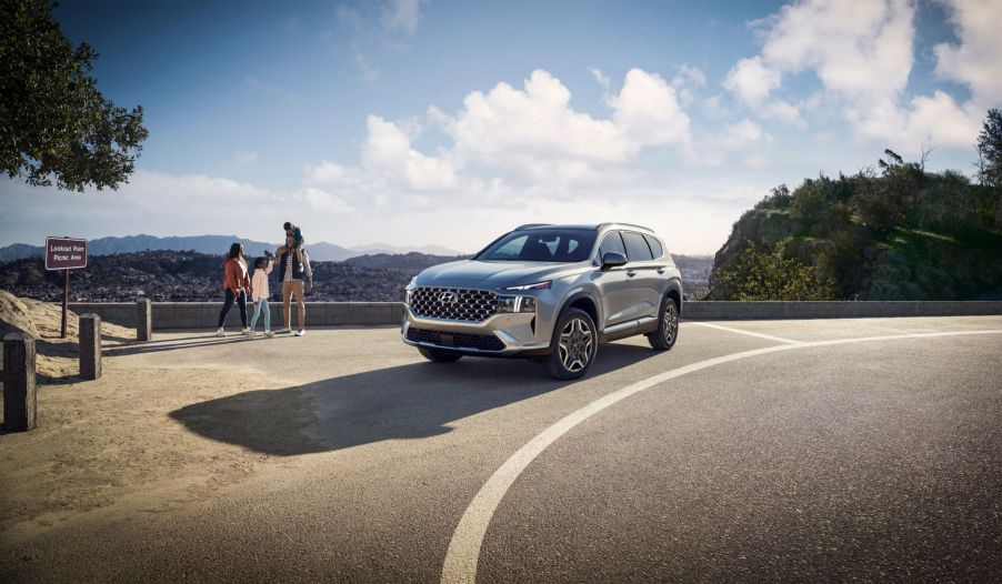 A silver gray 2023 Hyundai Santa Fe Plug-In Hybrid midsize crossover SUV model parked by a cliff overlook