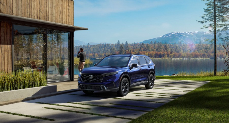 A blue 2023 Honda Consumer Reports-V parked in front of a building.