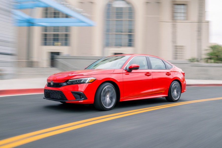 A red 2023 Honda Civic Sedan driving around a bend