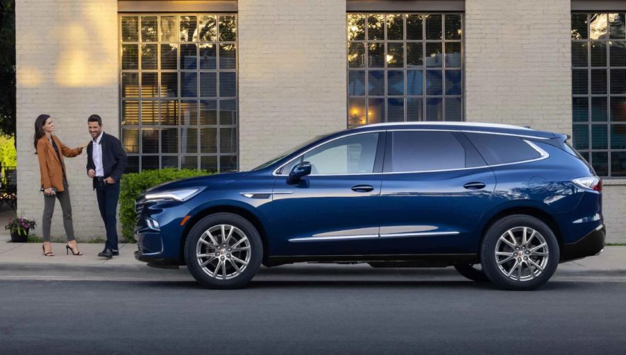 A dark blue 2023 Buick Enclave three-row midsize luxury crossover SUV side profile shot