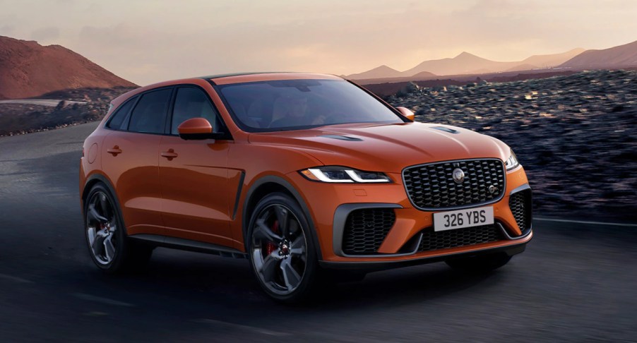 An orange Jaguar F-PACE is driving on the road.