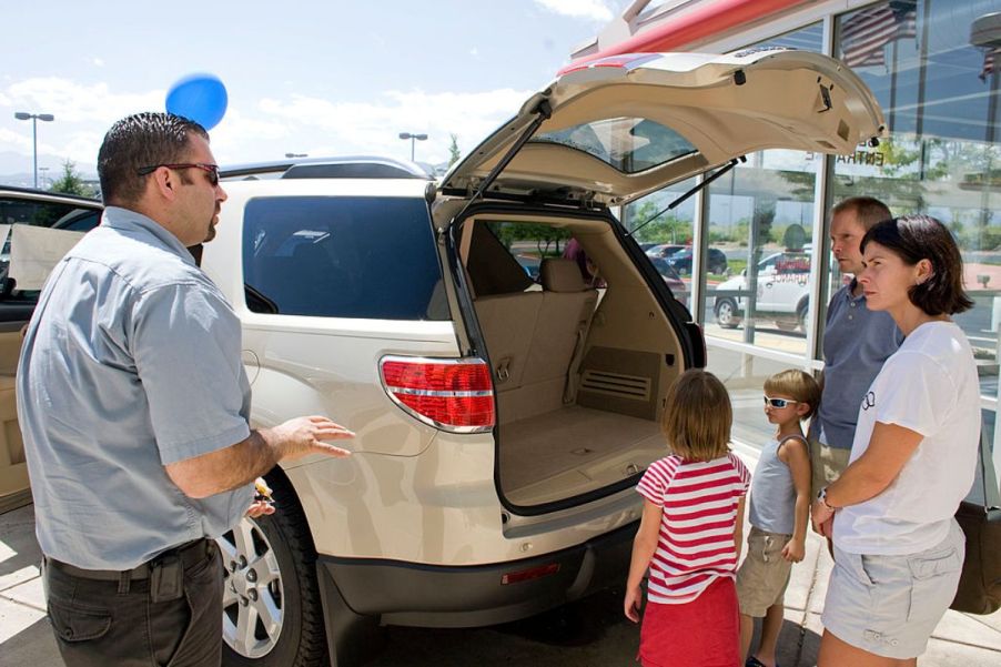 A family at a car dealership looking at a Saturn Outlook.