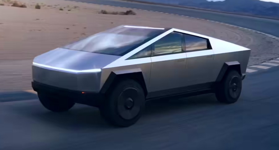 A gray 2024 Tesla Cybertruck electric pickup truck is driving on the road.