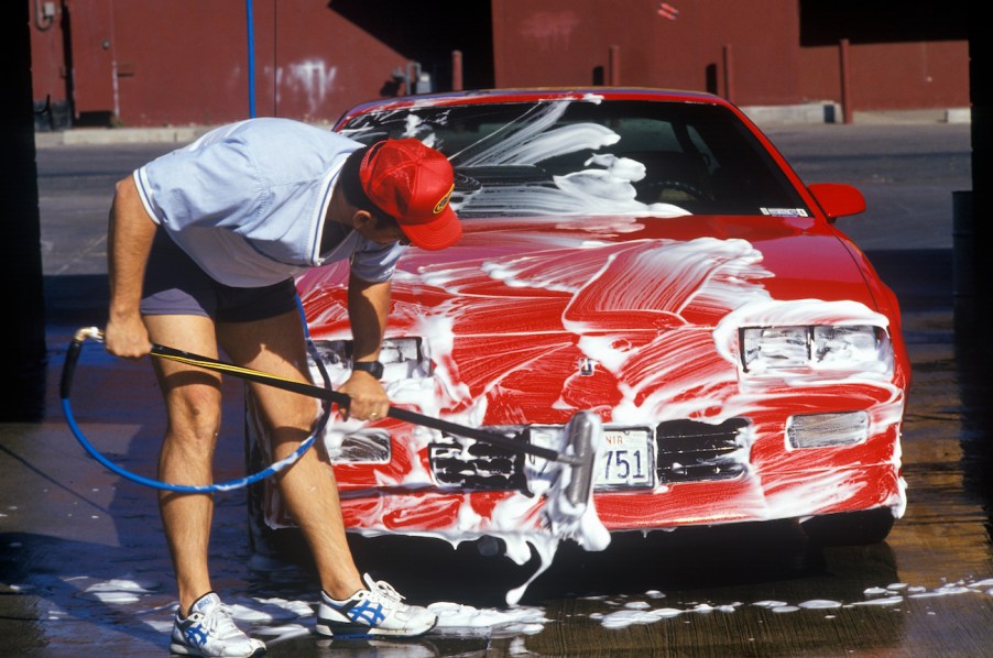 A man washing his red car