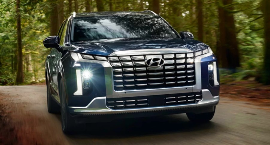 A blue 2023 Hyundai Palisade midsize SUV is driving off-road.