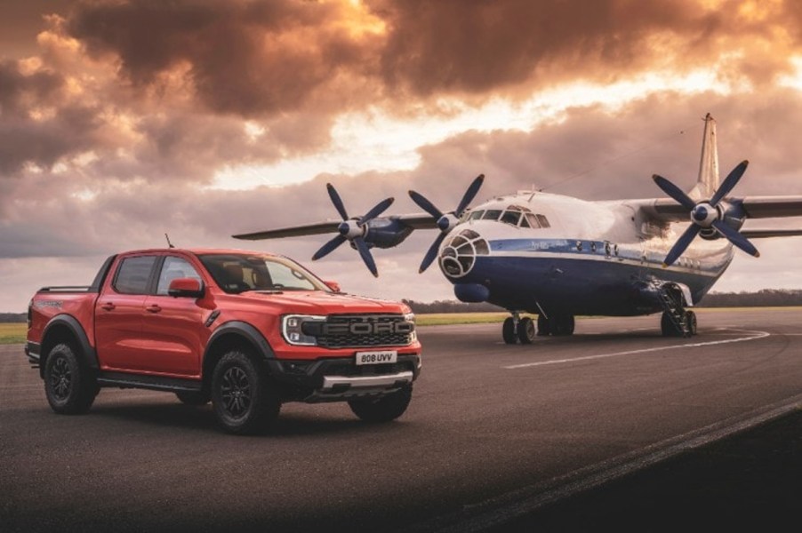 A Ford Ranger Raptor mid-size truck sits in front of a plane.