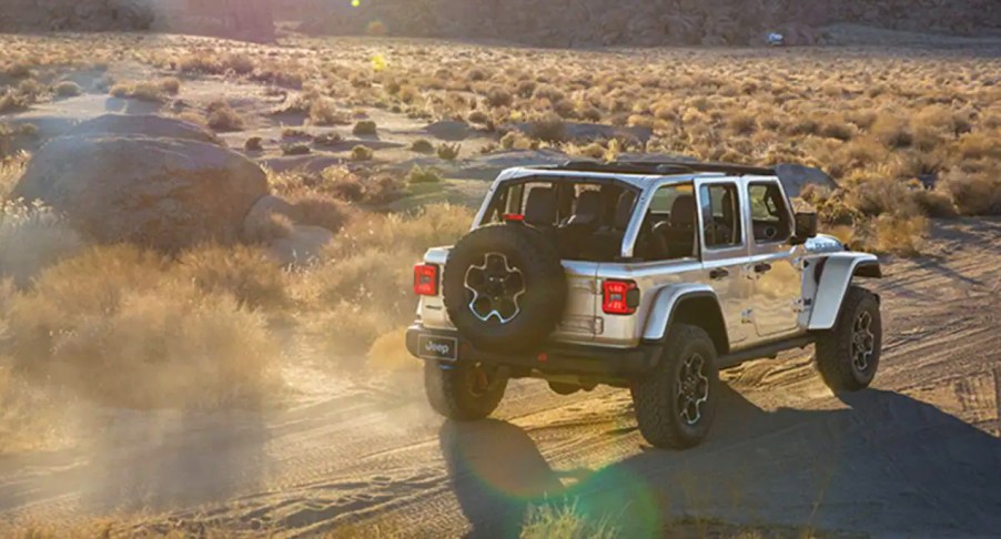 A gray 2023 Jeep Wrangler small SUV is driving off-road.