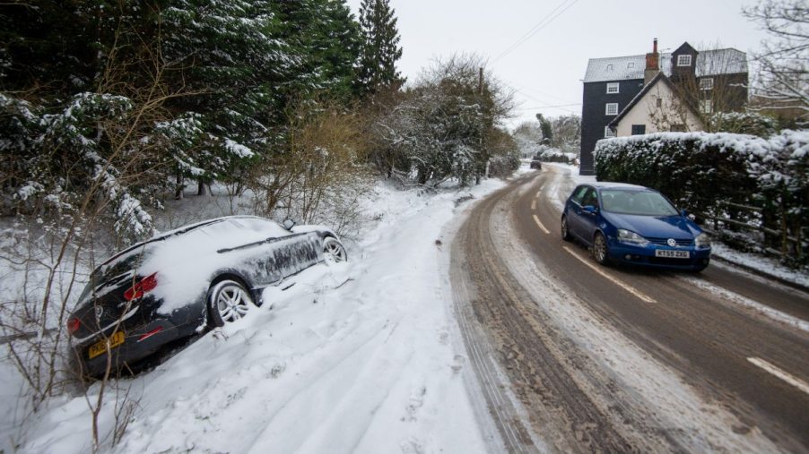 Vehicle stuck in snowy ditch, showing trick to correct slide on icy road to regain control of car