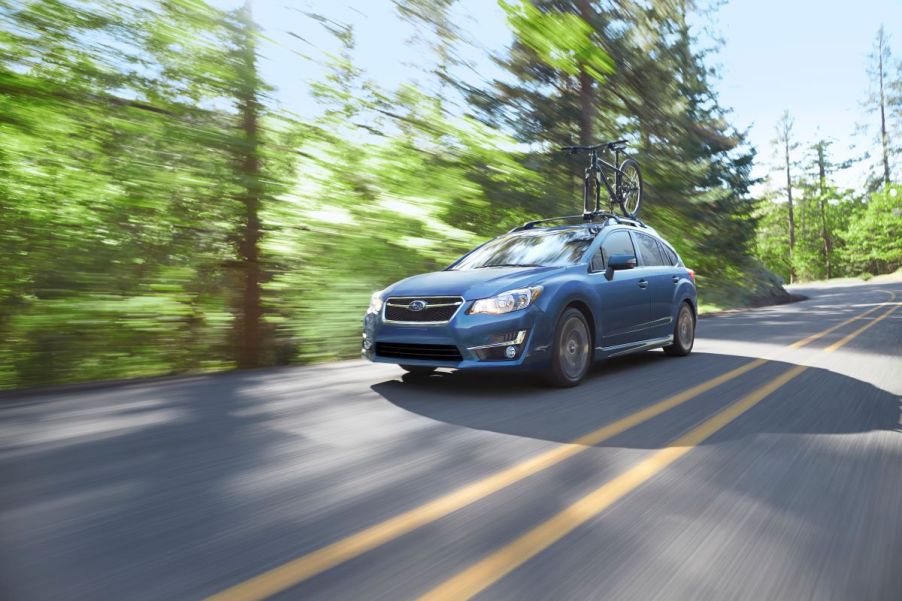 A blue Subaru hatchback drives down a road