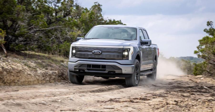 A Ford F-150 Lightning Lariat all-electric pickup truck model driving off-road on a worn dirt trail