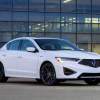 A white 2021 Acura ILX parked in front of a glass wall of a building.