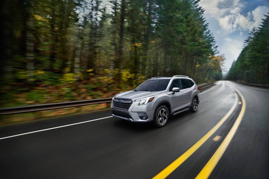 A silver Subaru Forester drives on a forest road.