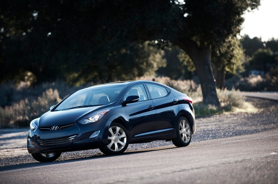 A blue 2013 Hyunda Elantra model corners on a country road.