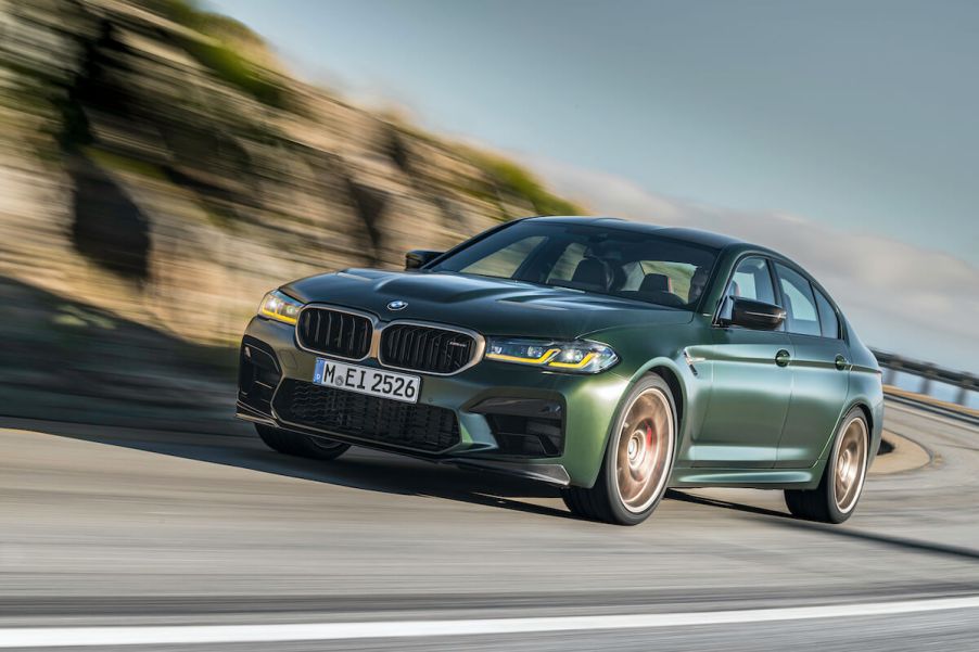 A front view of the 2023 BMW M5 driving down a road.