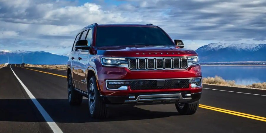 A red 2023 Jeep Wagoneer full-size SUV is driving on the road.