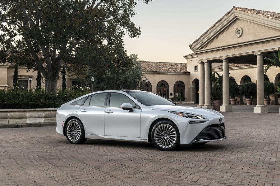 A white Toyota Mirai parked in front of a luxury house