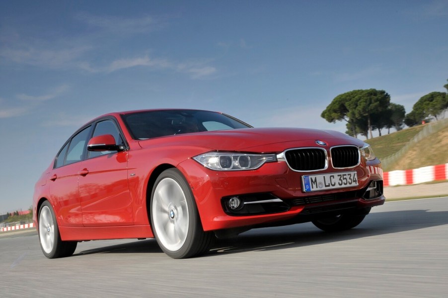 A used red 2014 BMW 328i cruises a coastal road.