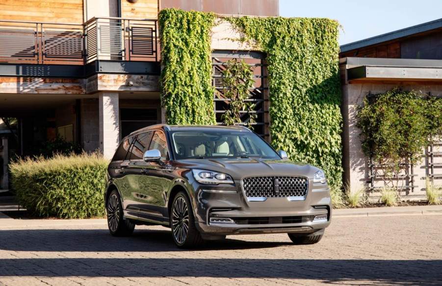 A new Lincoln Aviator its in front a luxury home covered in ivy.