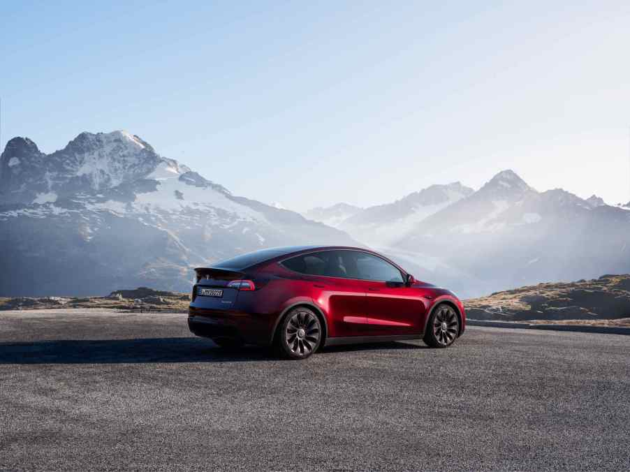 A red Tesla Model Y with mountains in the background.