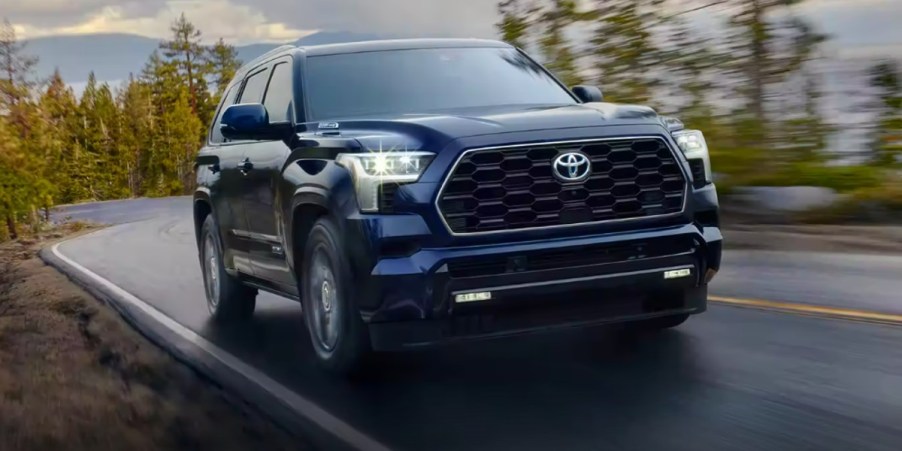 A blue 2023 Toyota Sequoia full-size SUV is driving on the road.