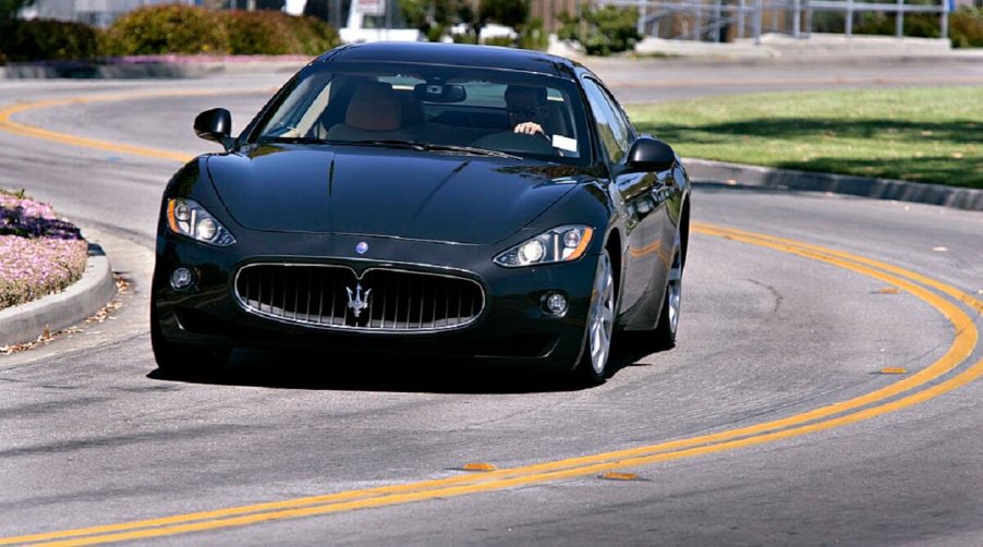 A used 2008 Maserati GranTurismo corners on a city street.